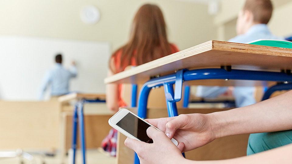 elev med mobilen i hand i klassrum