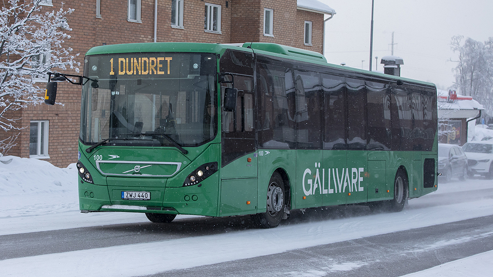 Buss kommer körande på en vintrig gata 